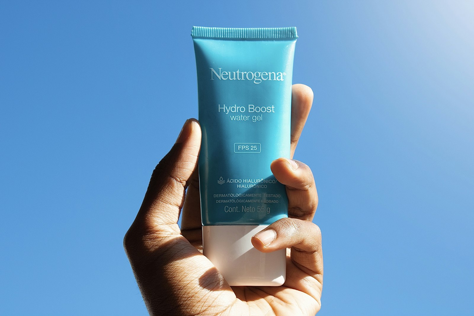 Mano che tiene un tubetto di crema controluce, etichetta in vista